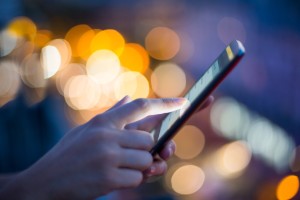 Woman using her mobile phone , city skyline night light  background