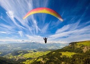 Paraglider flying over mountains in summer day