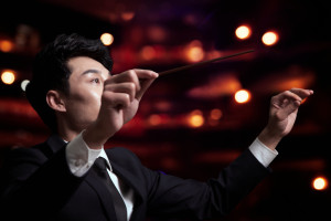 Young conductor with baton raised at a performance